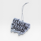 A white and black die-cut car air freshener featuring the stylized text 'TANTUM TRADES' in a dripping graffiti font, suspended by a thin white string against a light gray background.