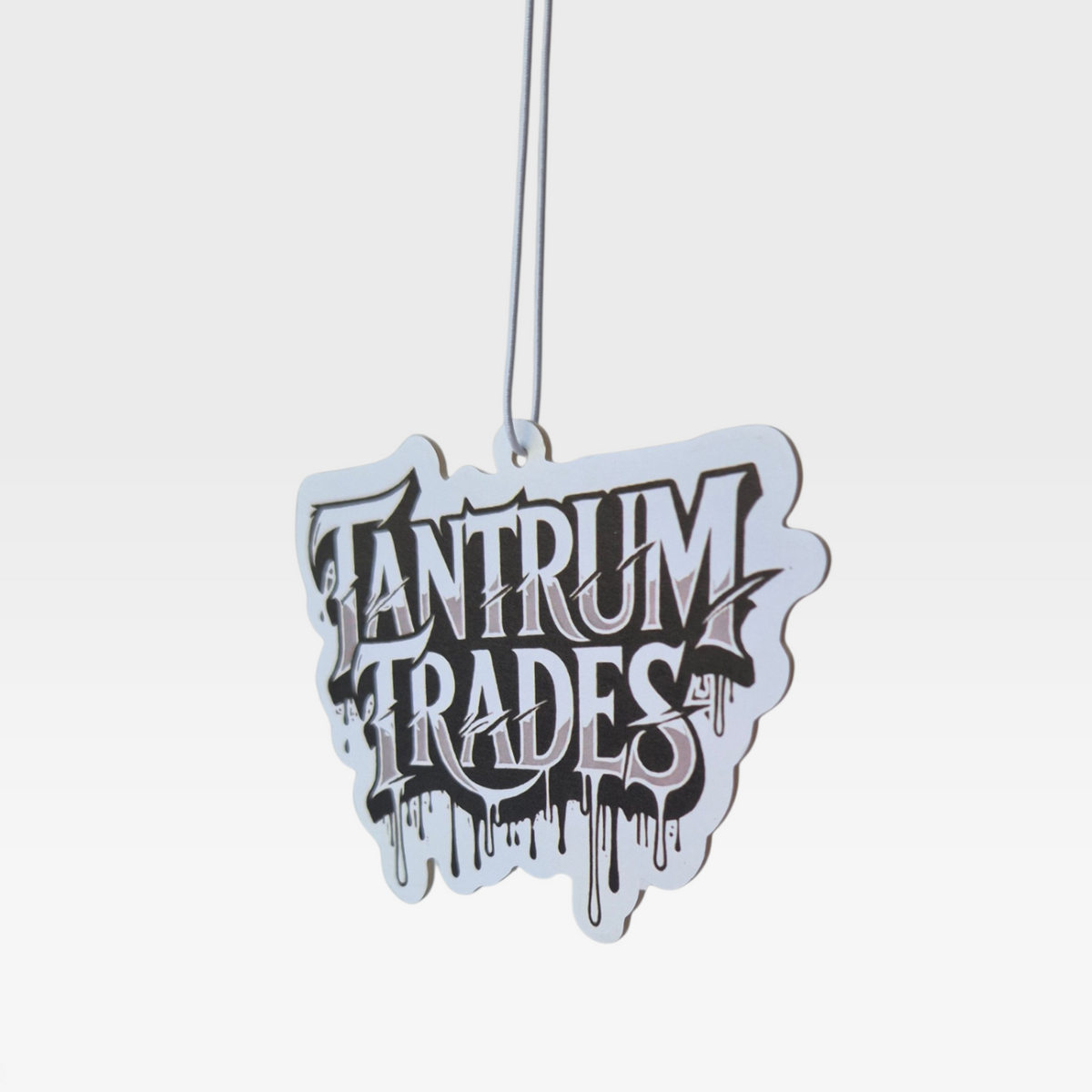 A black and white die-cut car air freshener with black graffiti-style text reading 'TANTRUM TRADES' shown on a plain light gray background.